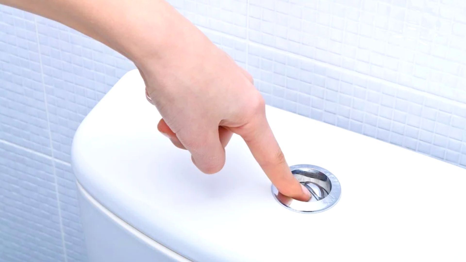 Person Pressing Flush Button On Top Of Toilet