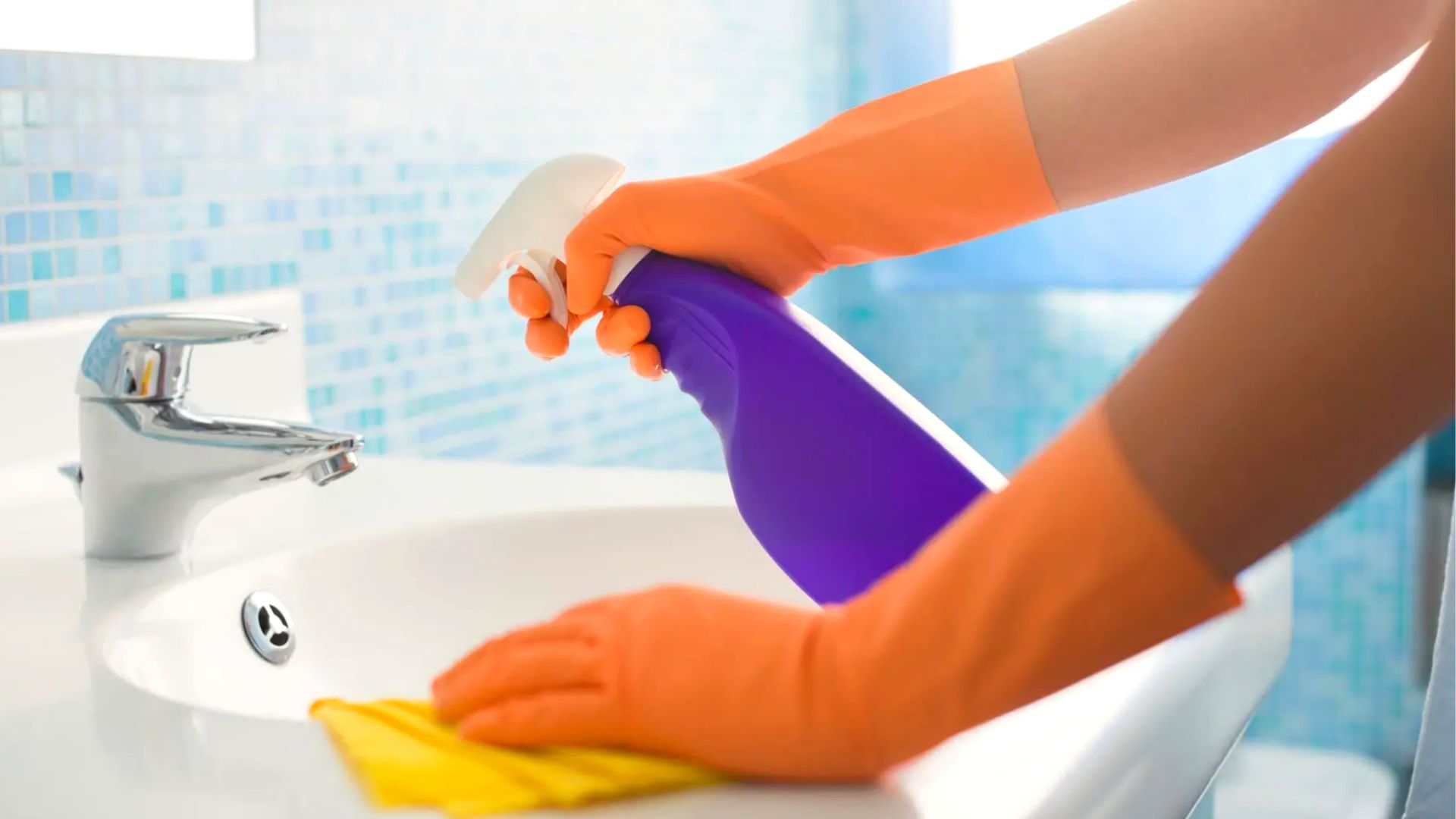 Person Cleaning Sink With Spray Bottle And Cloth