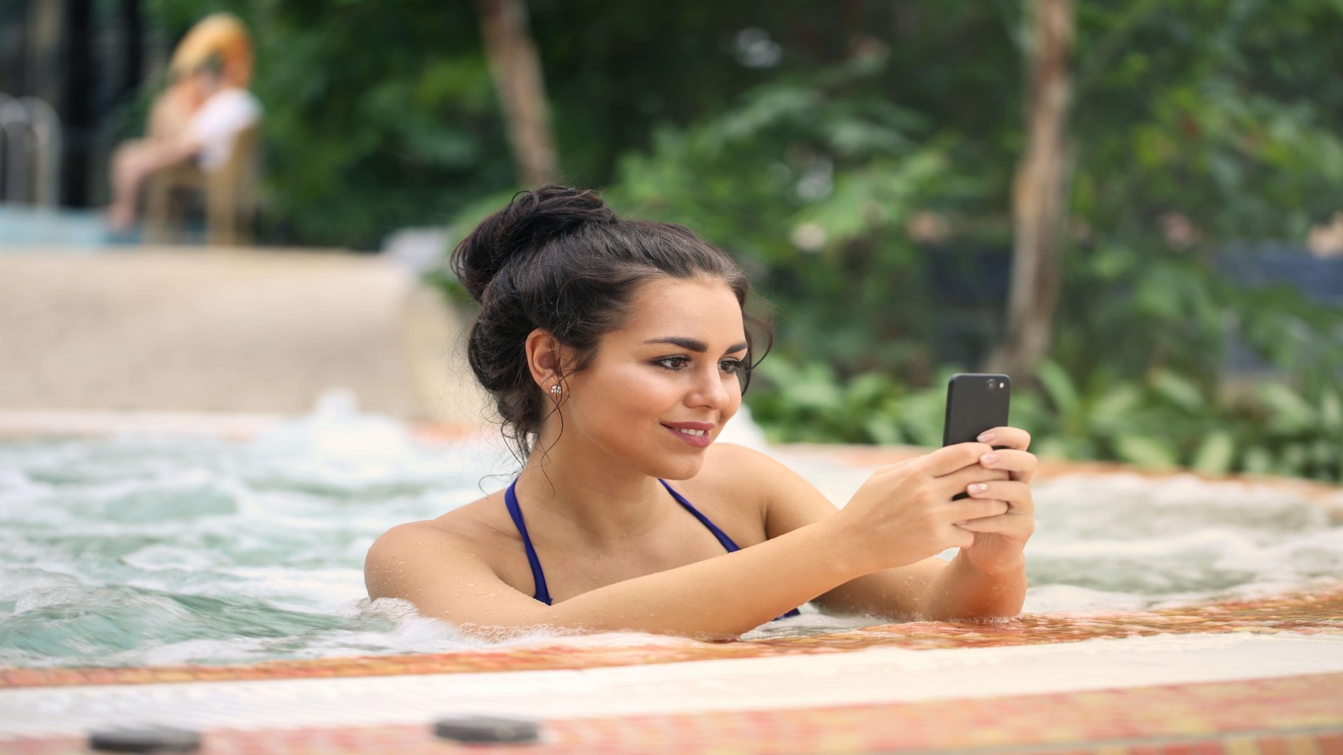 Woman In Swimming Pool With Her Phone